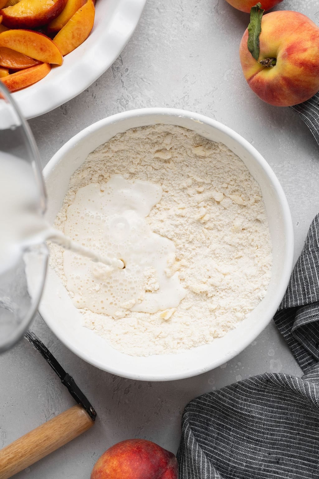Milk being poured into a bowl of dry ingredients to make pastry dough.