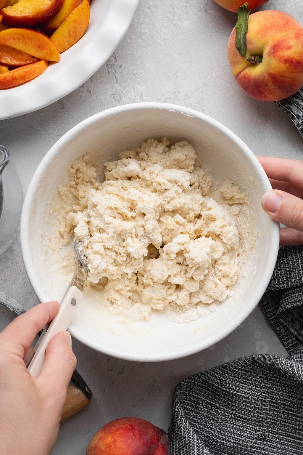 A woman stirring peach cobbler dough in a bowl.