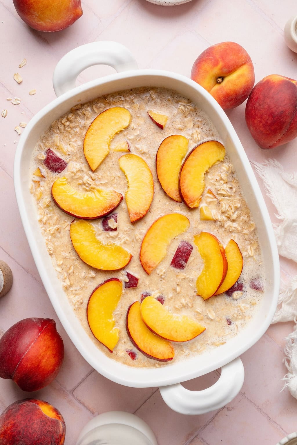 Uncooked peach baked oatmeal in a white rectangular baking dish.